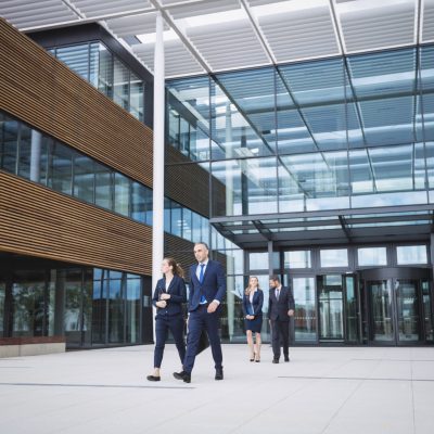 Group of business people walking outside the entrance of an office building